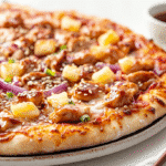 Teriyaki chicken pizza with pineapple, red onions, and sesame on ceramic plate